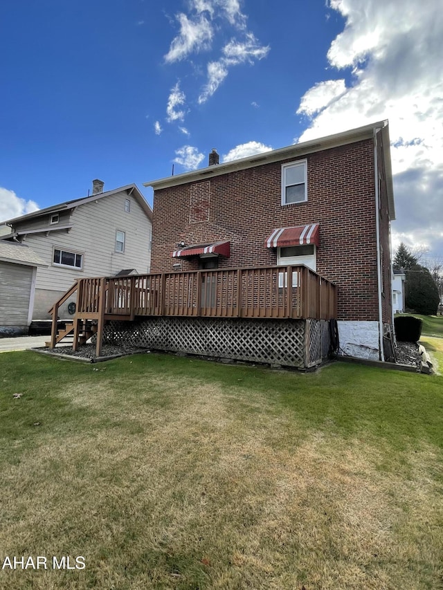 back of house featuring a lawn and a wooden deck