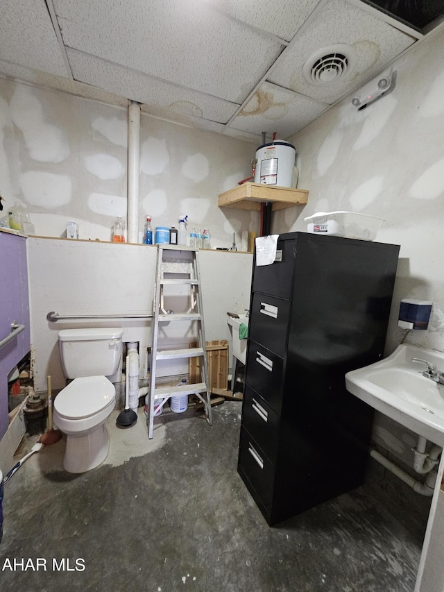 bathroom with a paneled ceiling, toilet, and concrete floors