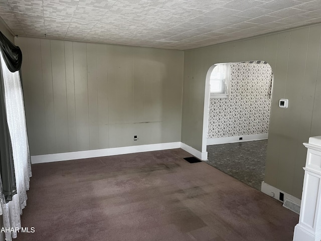 spare room featuring visible vents, dark carpet, and baseboards