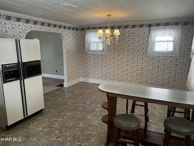 dining area featuring arched walkways, baseboards, wallpapered walls, an inviting chandelier, and crown molding