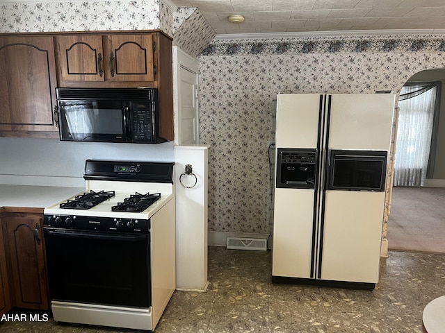 kitchen with wallpapered walls, white refrigerator with ice dispenser, range with gas stovetop, light countertops, and black microwave