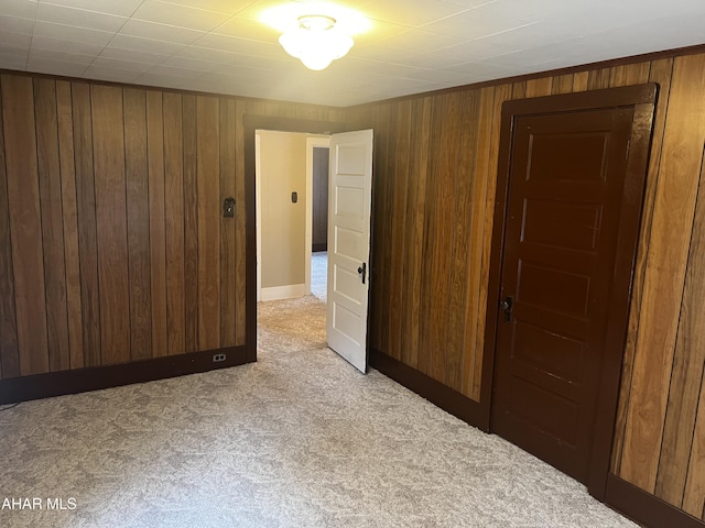 unfurnished room featuring light carpet and wood walls