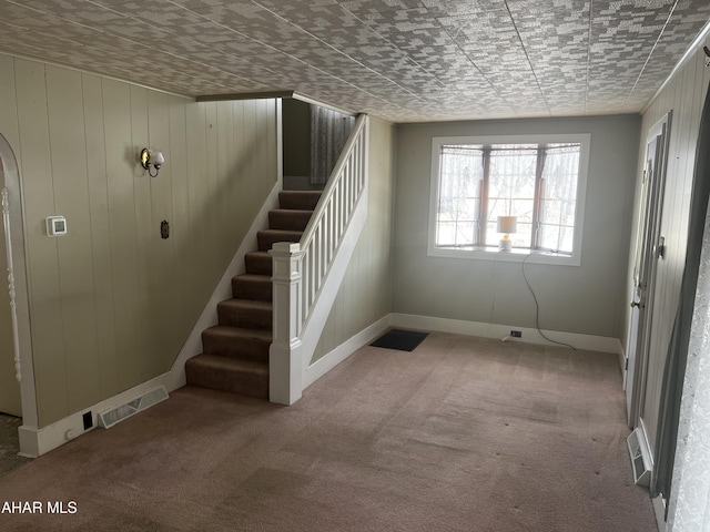 interior space with carpet floors, wood walls, and visible vents