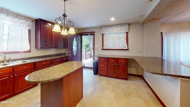 602 5th Ave, Altoona, PA 16602 - kitchen with a sink, dark brown cabinets, decorative light fixtures, a center island, and light stone countertops