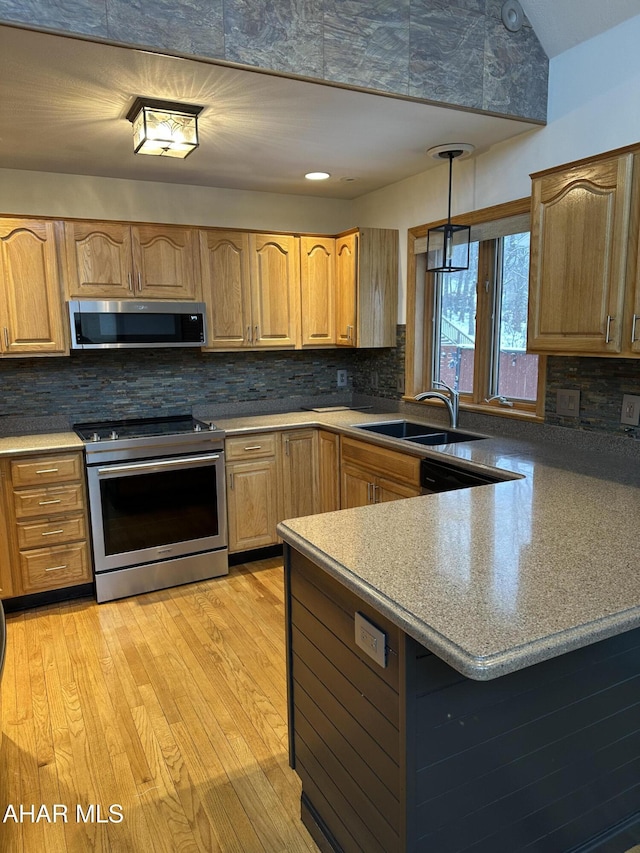 kitchen with tasteful backsplash, light wood-type flooring, appliances with stainless steel finishes, and a sink