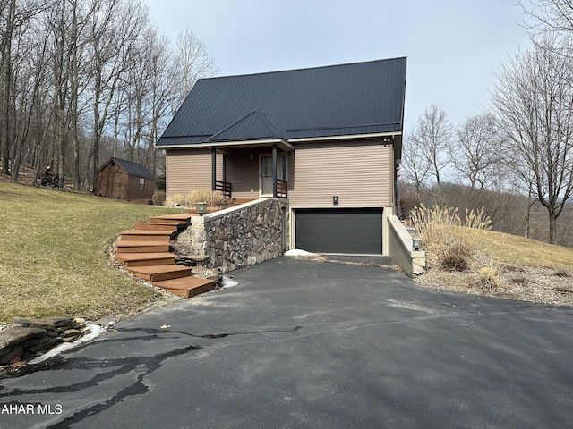 view of front of house featuring metal roof, a front lawn, an attached garage, and driveway