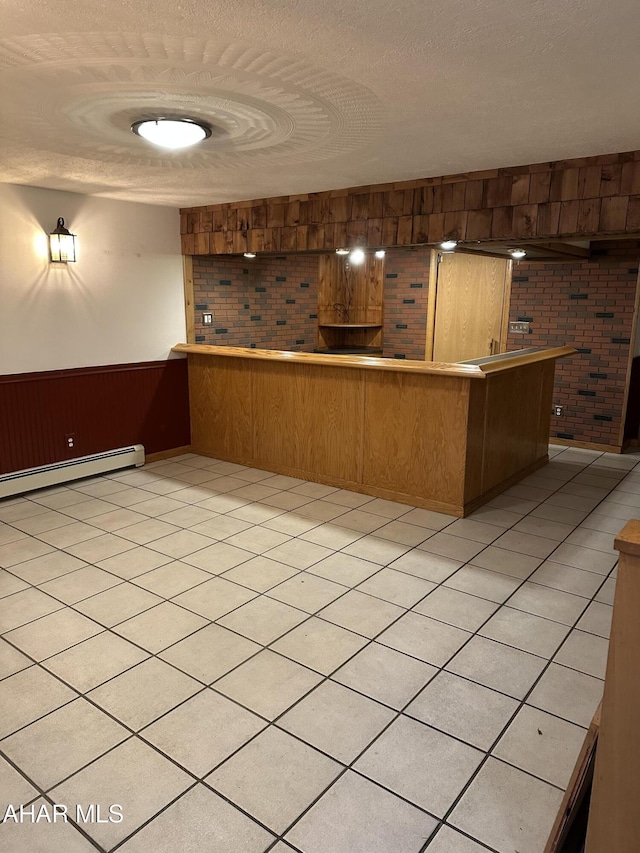 bar with a wainscoted wall, a textured ceiling, a community bar, and a baseboard radiator