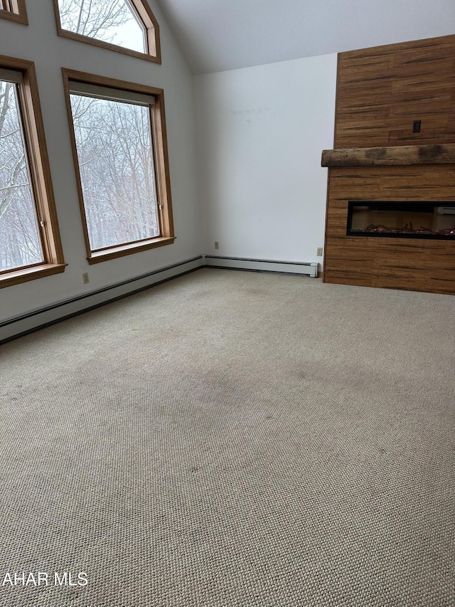 unfurnished living room featuring lofted ceiling, carpet floors, a healthy amount of sunlight, and a glass covered fireplace