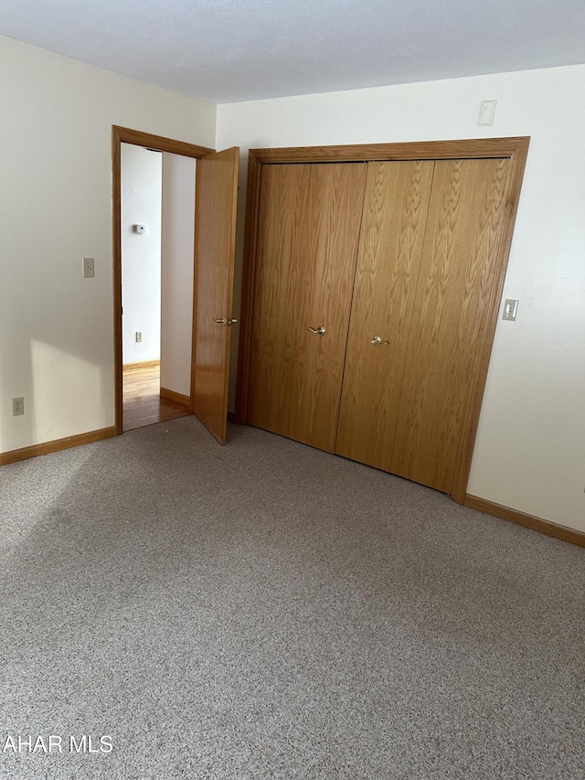 unfurnished bedroom featuring carpet, baseboards, and a closet