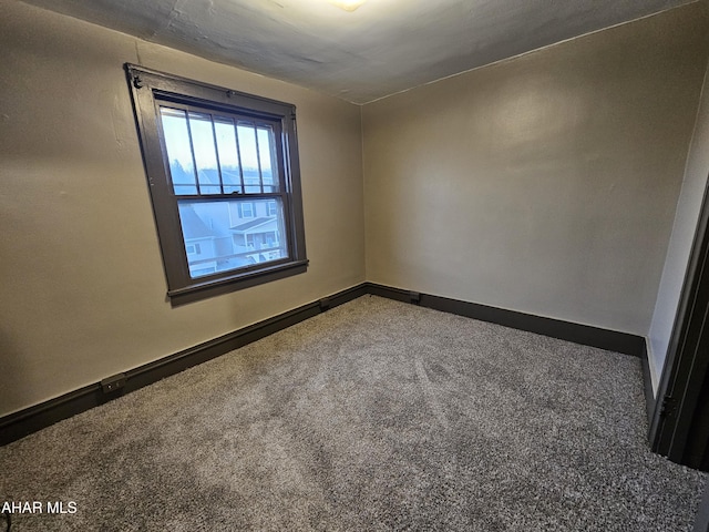 carpeted empty room featuring baseboards