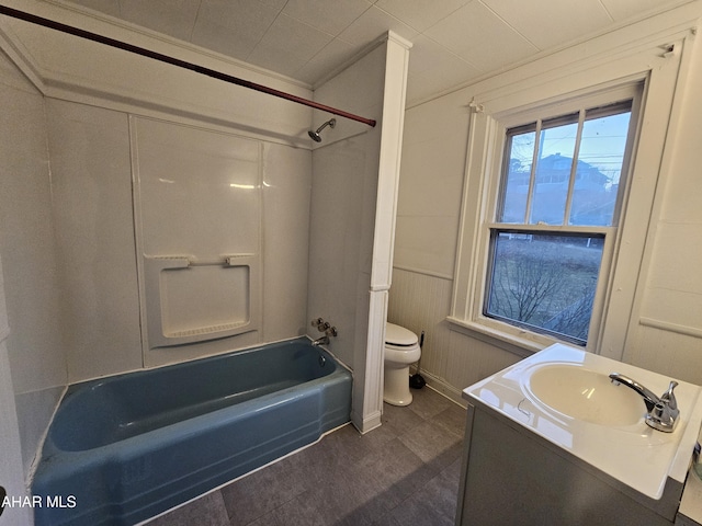 bathroom with a decorative wall, toilet, vanity, and  shower combination