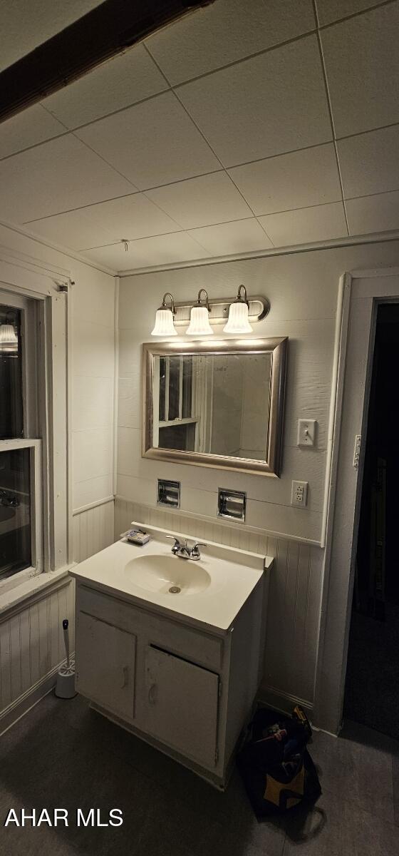 bathroom with vanity, a drop ceiling, and wainscoting