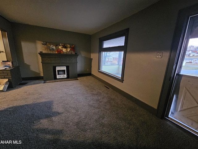 unfurnished living room with a fireplace with flush hearth, carpet flooring, visible vents, and baseboards