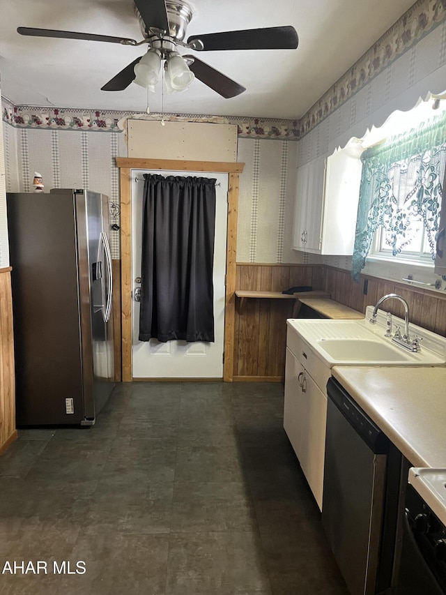 kitchen featuring appliances with stainless steel finishes, ceiling fan, wooden walls, and sink