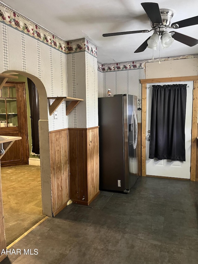 kitchen with wooden walls, ceiling fan, and stainless steel refrigerator with ice dispenser