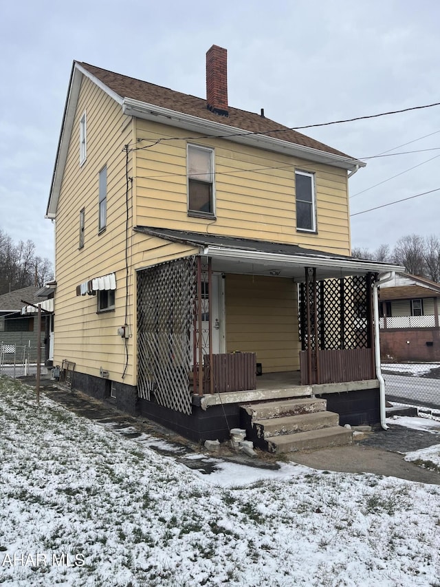 snow covered rear of property with covered porch