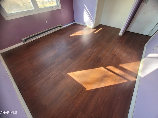 interior space with a baseboard heating unit and wood finished floors