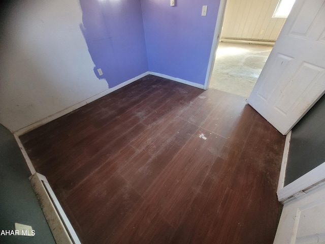 spare room with dark wood-style flooring and baseboards