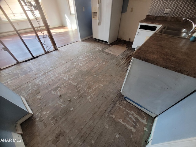 kitchen featuring dark countertops, hardwood / wood-style floors, white refrigerator with ice dispenser, and a sink