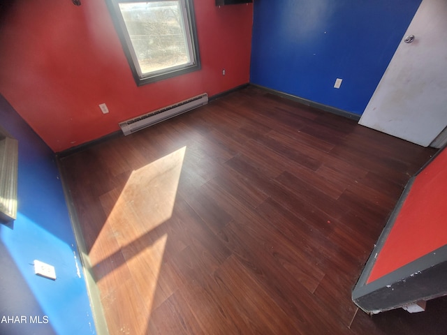 empty room featuring baseboards, baseboard heating, and wood finished floors