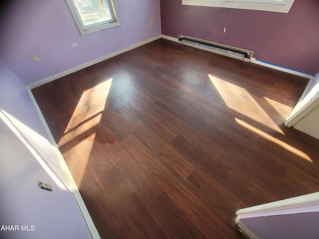 spare room featuring a baseboard radiator, wood finished floors, and baseboards