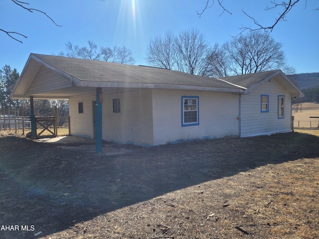 view of side of property featuring fence and roof with shingles