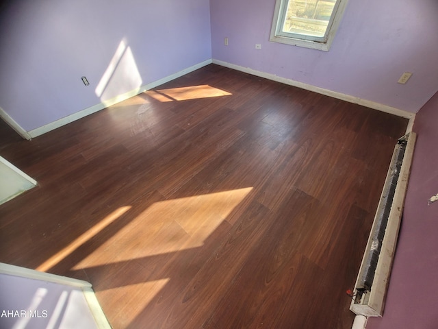 spare room featuring dark wood finished floors and baseboards