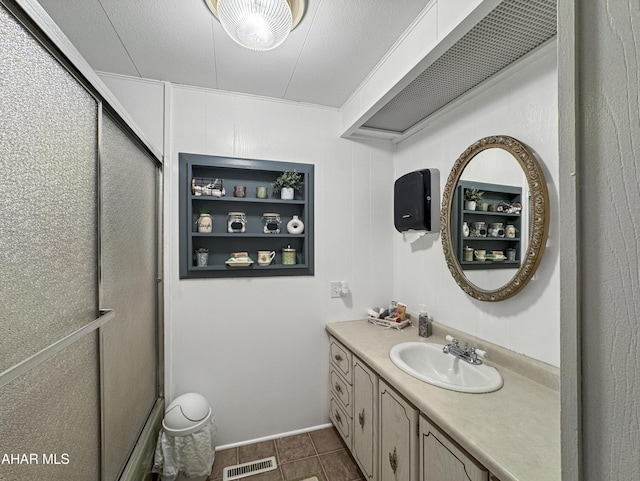 bathroom featuring tile patterned floors, vanity, a shower with shower door, and a textured ceiling