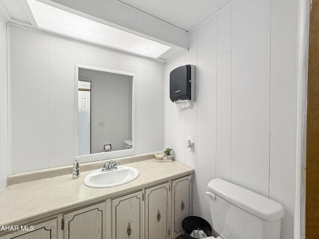 bathroom with wooden walls, vanity, and toilet