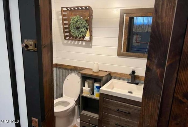 bathroom featuring vanity, toilet, and wood walls