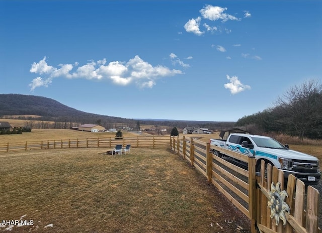 view of yard with a rural view, fence, and a mountain view