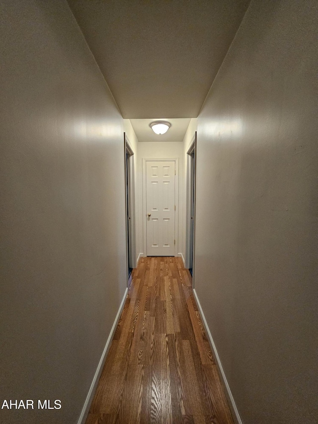 corridor with wood finished floors and baseboards