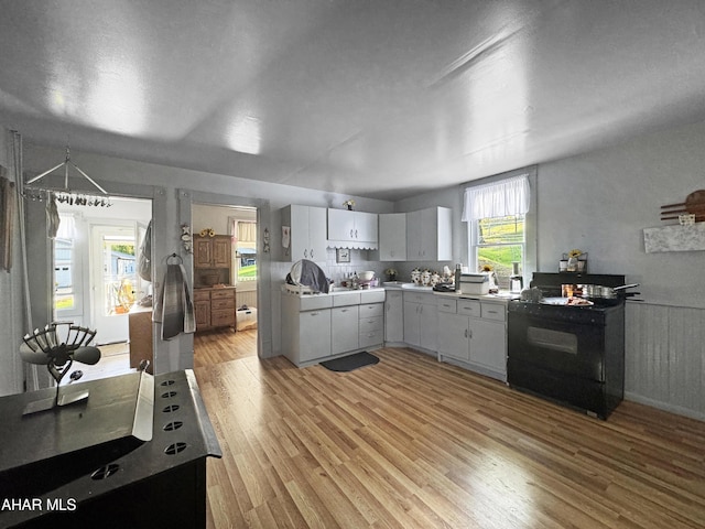 kitchen with white cabinets, black electric range oven, and light wood-type flooring