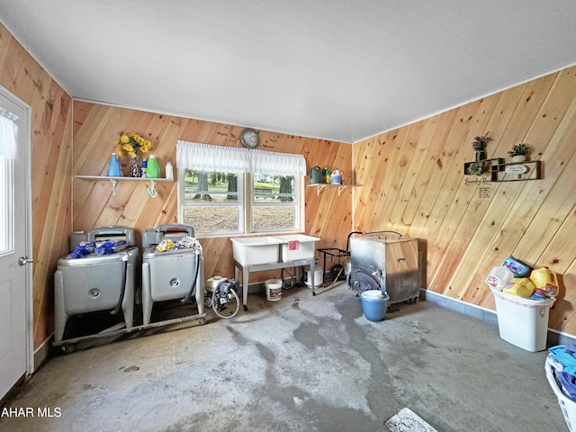 misc room featuring wooden walls, concrete flooring, and washer / dryer