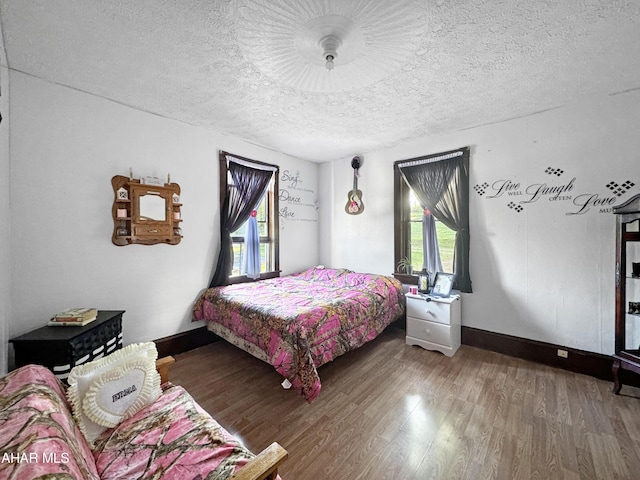 bedroom with hardwood / wood-style floors, a textured ceiling, and multiple windows