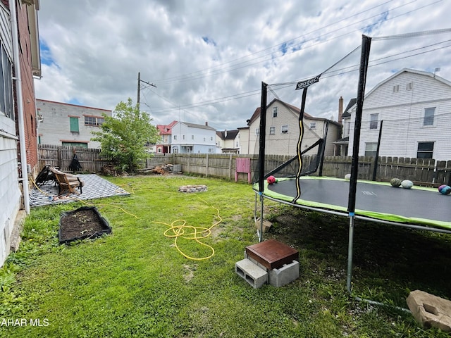 view of yard featuring a trampoline and a fire pit