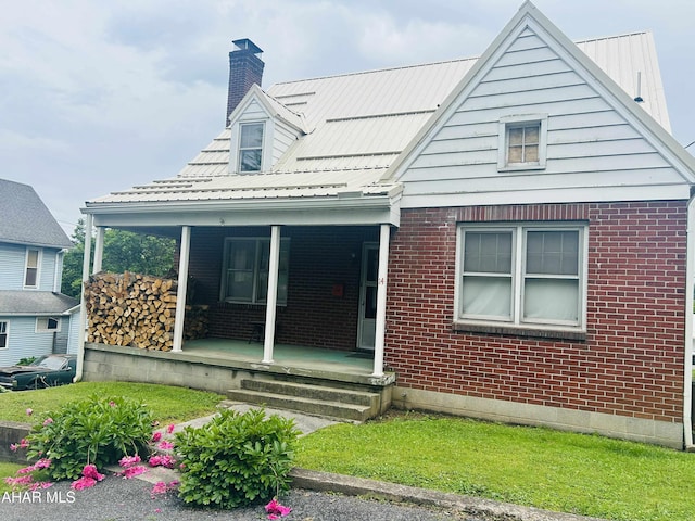 14 W 2nd St, Everett, PA 15537 - view of front of house featuring a porch, a chimney, brick siding, and a front lawn