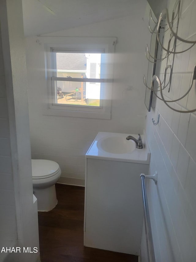 bathroom featuring vanity, lofted ceiling, toilet, tile walls, and wood-type flooring