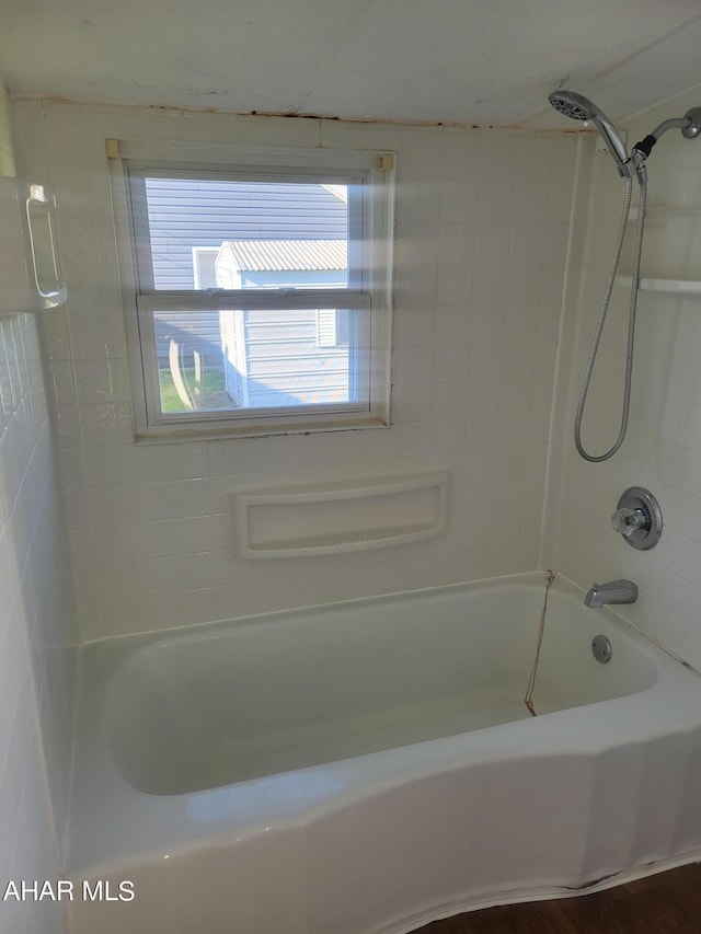 bathroom featuring wood-type flooring and tiled shower / bath