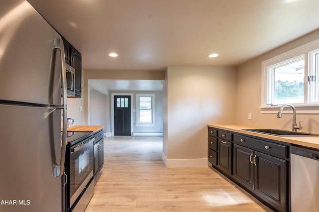 kitchen with sink, light hardwood / wood-style flooring, wooden counters, a baseboard heating unit, and stainless steel appliances