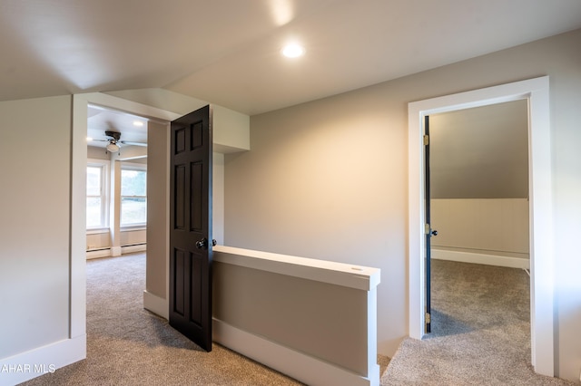 hall with a baseboard heating unit and light carpet