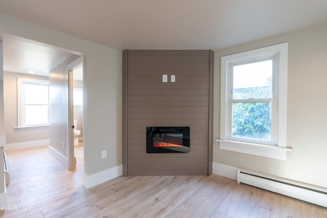 unfurnished living room featuring light hardwood / wood-style flooring, a fireplace, and a baseboard radiator