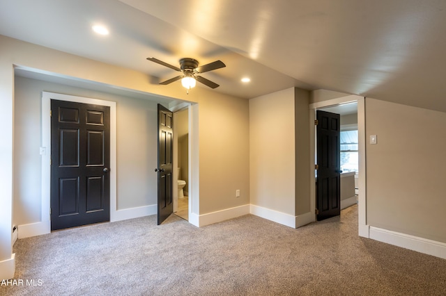 unfurnished bedroom featuring light colored carpet and ensuite bath