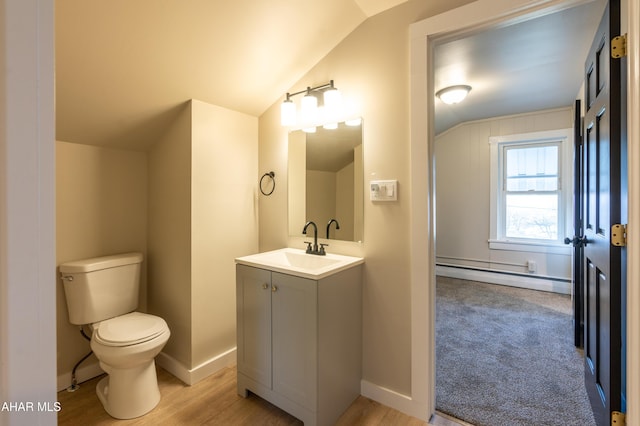 bathroom with wood-type flooring, lofted ceiling, vanity, a baseboard heating unit, and toilet