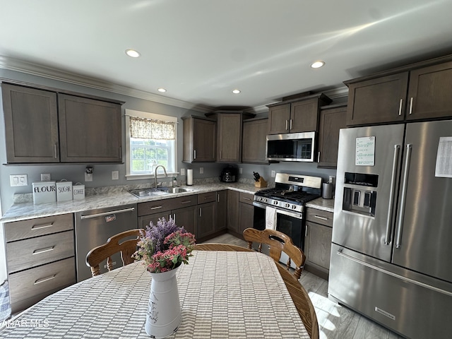 kitchen featuring dark brown cabinets, a sink, ornamental molding, stainless steel appliances, and recessed lighting