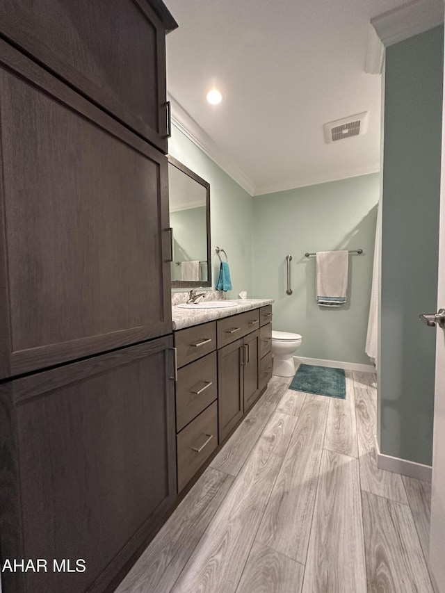full bathroom featuring crown molding, vanity, toilet, wood finished floors, and visible vents