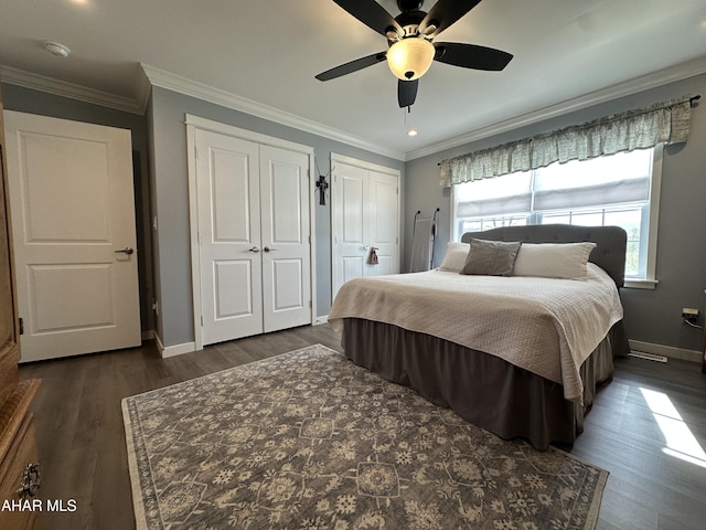 bedroom with baseboards, multiple closets, dark wood finished floors, and multiple windows