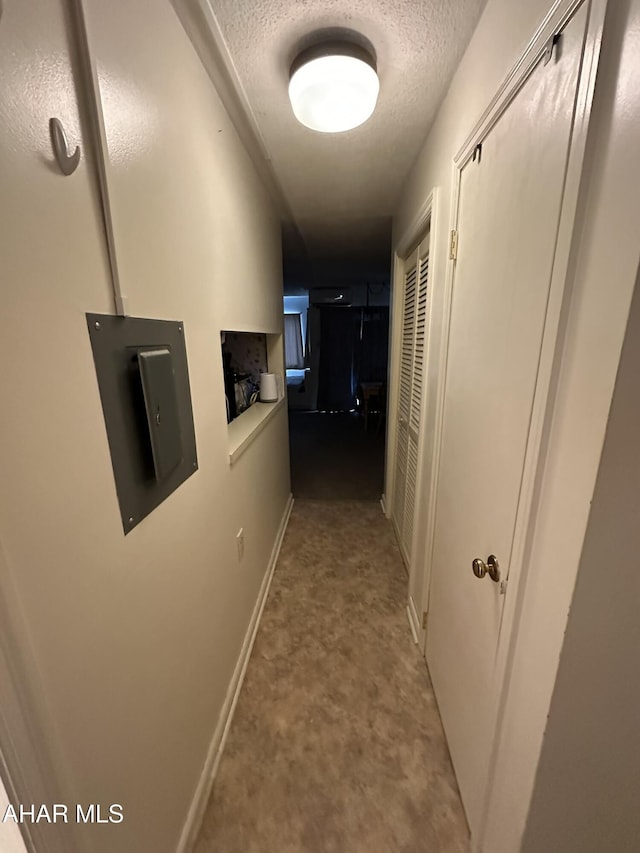 hall with light colored carpet and a textured ceiling