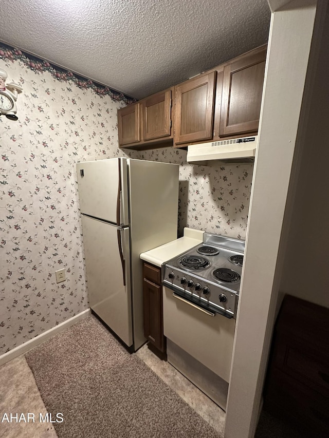 kitchen featuring electric range, a textured ceiling, and white fridge