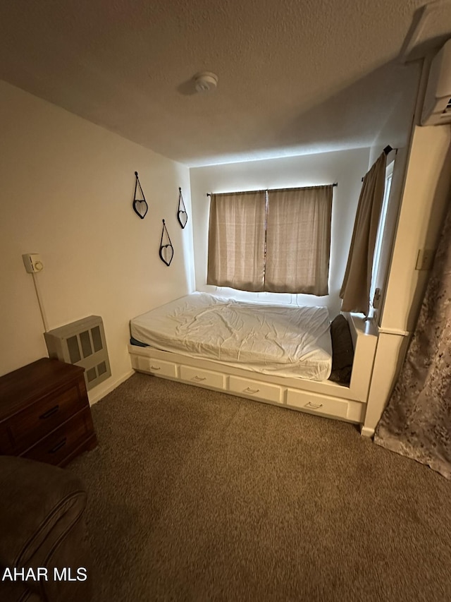 unfurnished bedroom featuring dark colored carpet, a wall unit AC, and a textured ceiling